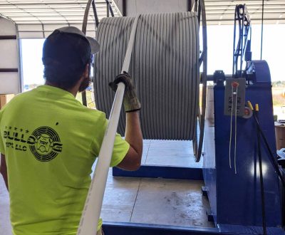 A man in a yellow shirt is working on a large metal pipe used for standard HDPE conduit.