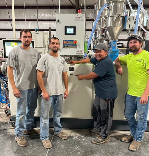 Four career-driven men standing in front of a machine at Bulldog Pipe LLC.