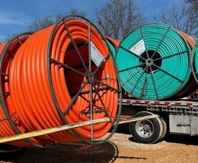 A truck equipped with several standard HDPE conduits displaying orange and green conduit pipe.